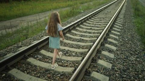 Kid walking on rail track stepping on gravel in rural setting Video stock 310217873