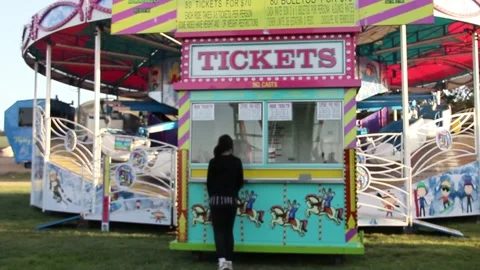 Kid walks up to an empty ticket booth at a deserted carnival Stock Footage 154940076