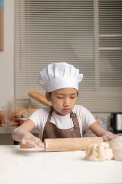 The kid ware a white chef hat and brown apron. Stock Photos