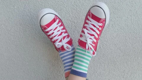 Kid wearing different pair of socks. Child legs up in mismatched socks on gray Stock Footage 201382453