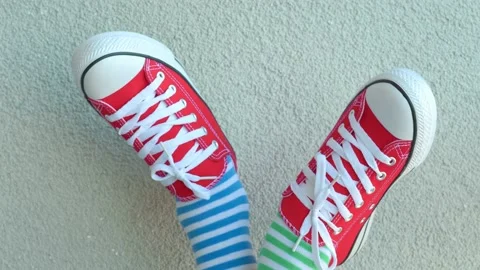 Kid wearing different pair of socks. Child legs up in mismatched socks on gray Stock Footage 201487994