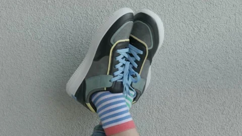 Kid wearing different pair of socks. Child legs up in mismatched socks on gray Stock Footage 201488781