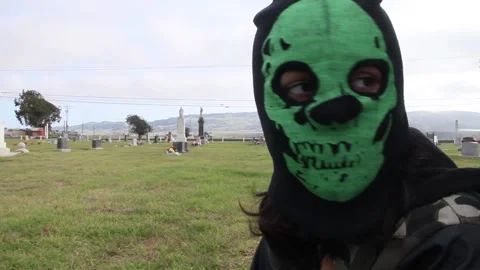 Kid wearing skeleton mask at graveyard Stock Footage 155385148