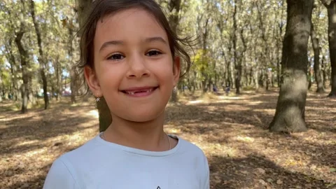 A kid without two front teeth smiles in an autumn park Video stock 302086441