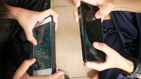 Kids are playing Mobile Legends games applications on their mobile phones. Stock Footage