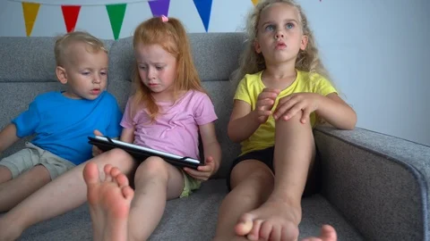 Kids arguing for playing with digital tablet on a sofa. Addictive friends Stock Footage 126780198