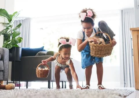 Kids, basket and easter egg hunt in home, pick up treats and celebration to.. Stock Photos