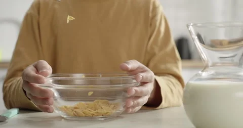 Kid's breakfast. Close-up corn flakes falling into kid's bowl. Cereal Stock Footage 267027482
