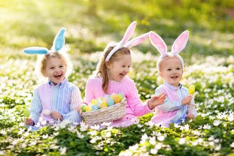 Kids with bunny ears on Easter egg hunt. Stock Photos