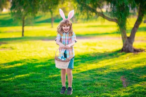 Kids in bunny ears on Easter egg hunt in garden. Children with colorful eggs in Stock Photos