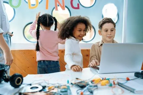 Kids in classroom learning about programming remote car with laptop. Erudition. Stock Photos
