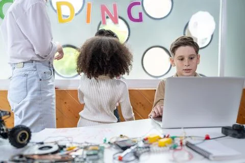 Kids in classroom learning about programming remote car with laptop. Erudition. Stock Photos