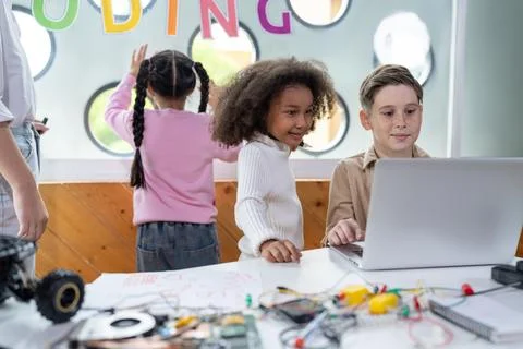 Kids in classroom learning about programming remote car with laptop. Erudition. Stock Photos