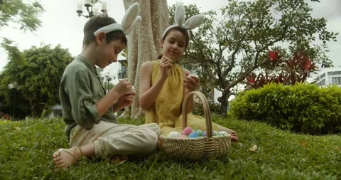 Kids collects Easter eggs and girl puts in a basket. Children are sitting on the Stock Footage 304815893