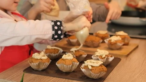 Kids decorating cupcakes with cream while cooking in kitchen Stock Footage 261735233