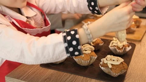 Kids decorating cupcakes with cream while cooking in kitchen Stock Footage 261735270
