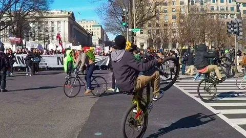 Kids do bike tricks in front of political protest Video stock 72350107