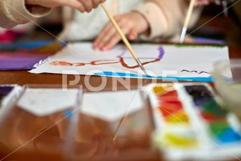 Kids drawing and a lot of painting tools on a wooden background Stock Photos
