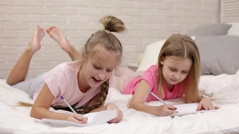 Kids drawing pictures while lying on bed. Stock Footage 108508618