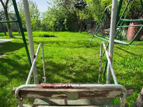 Kids empty swing in the backyard of your own house on a hot summer day, copy Stock Photos