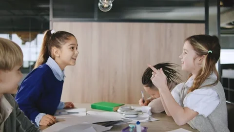 Kids engage in lively discussion while working on group project at modern Stock Footage 331307013