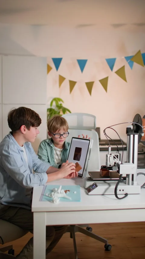 Kids examine and test a 3D printed part in their hands, near working 3D printer Stock Footage 335394858