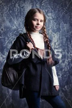 Kid's fashion. A cute modern girl is posing on grunge background at at the st Stock Photos