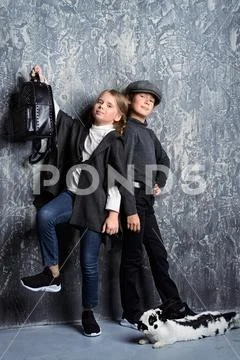 Kid's fashion. Two modern children posing together at studio. Clothes for chi Stock Photos