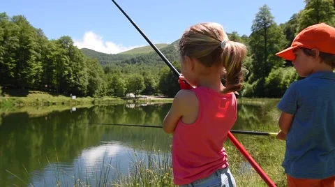 Kids fishing by mountain lake in summer Stock Footage