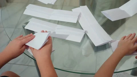 Kids folding paper on table surrounded by crafting tools and folded paper Stock Footage 306690751