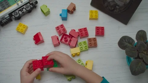 Kids hands playing with constructor on the white wooden table. Building toy Vídeos de archivo 123790409