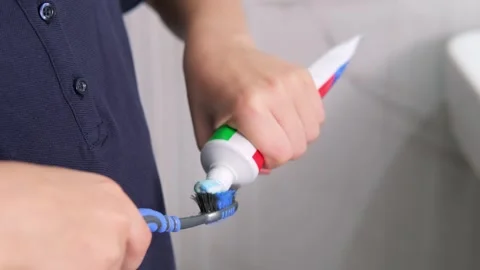 Kids hands squeeze toothpaste onto toothbrush in bathroom at home, Health care Stock Footage 246143064