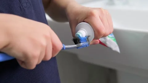 Kids hands squeeze toothpaste onto toothbrush in bathroom at home, Health care Stock Footage 246143106
