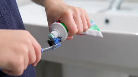 Kids hands squeeze toothpaste onto toothbrush in bathroom at home, Health care Stock Footage 246605651