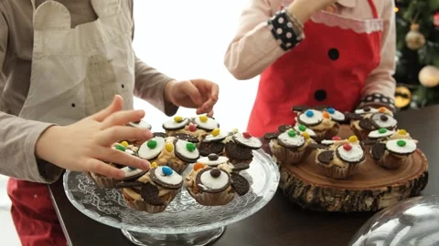 Kids having fun with cupcakes on serving stand after cooking in kitchen Stock Footage 261735628