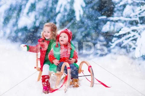 Kids having fun on a sleigh ride in winter Stock Photos