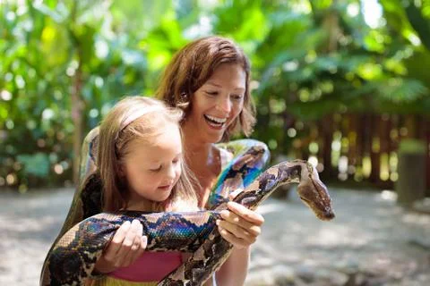 Kids hold python snake at zoo. Child and reptile. Stockfoto's