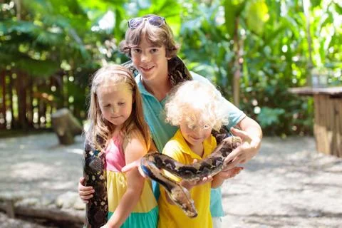 Kids hold python snake at zoo. Child and reptile. 스톡 사진