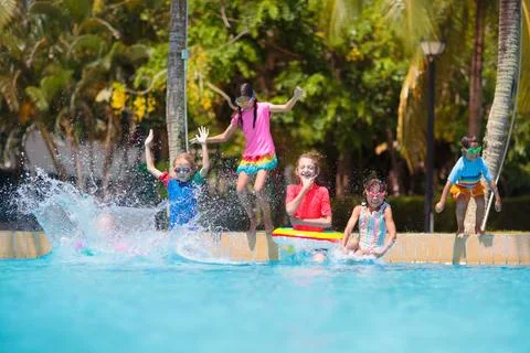 Kids jump into swimming pool. Summer water fun. Stock Photos