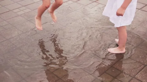 Kids jumping and having fun in puddle on city street Stock Footage 110892745