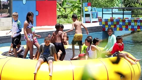 Kids Jumping on a Yellow Inflatable Trampoline on Summer Stock Footage 218188360