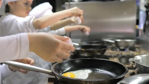 Kids learning how to cook eggs in a cooking class in restaurant kitchen Stock Footage 150312319