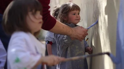 Kids learning how to paint on the wall and teacher helping with brush Stock Footage 47147913