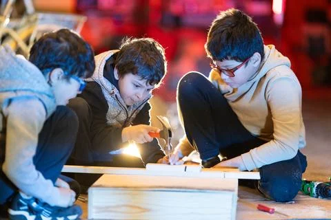 Kids learning woodworking using hand tools, developing practical skills Foto stock