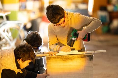 Kids learning woodworking using power drill in workshop Foto stock