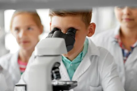 Kids or students with microscope biology at school Stock Photos