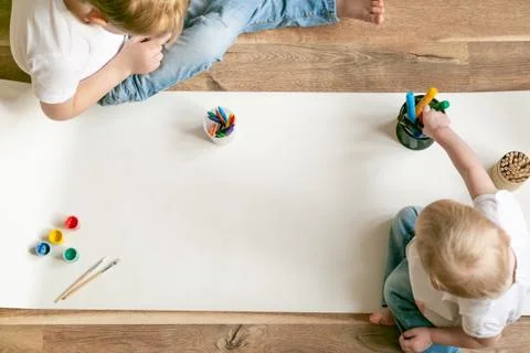 Kids painting with different materials on large canva on the flour Stock Photos