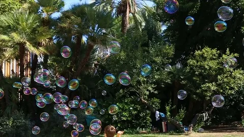 Kids play with bubbles. Lots of bubbles in the park in Barcelona, Spain on Stock Footage 75054330