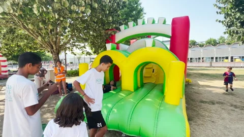 Kids playing and jumping energetically on a colorful inflatable obstacle course Stock Footage 313150931