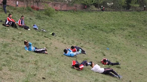Kids playing and rolling down a grass slope in the park Stock Footage 48710939